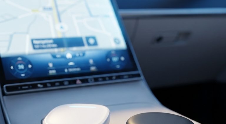 Interno di un'auto con schermo acceso e piccolo adattatore wireless bianco sulla console centrale